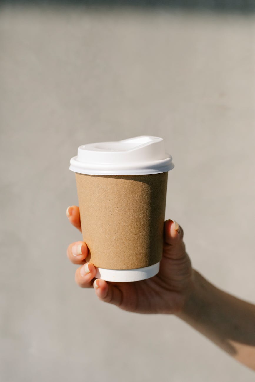 crop woman showing paper cup